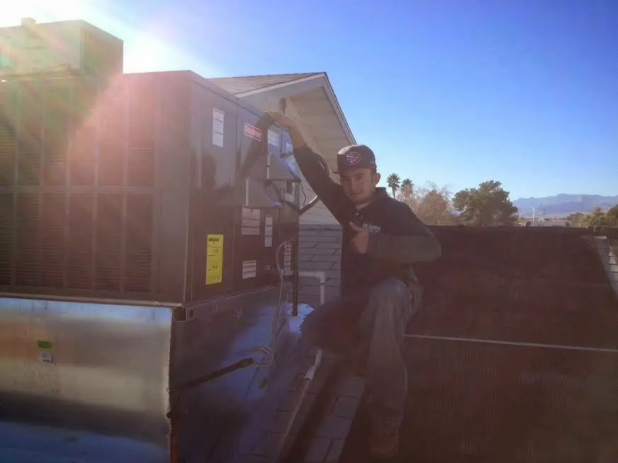 HVAC technician performing Air Duct Cleaning on a rooftop unit in Raleigh